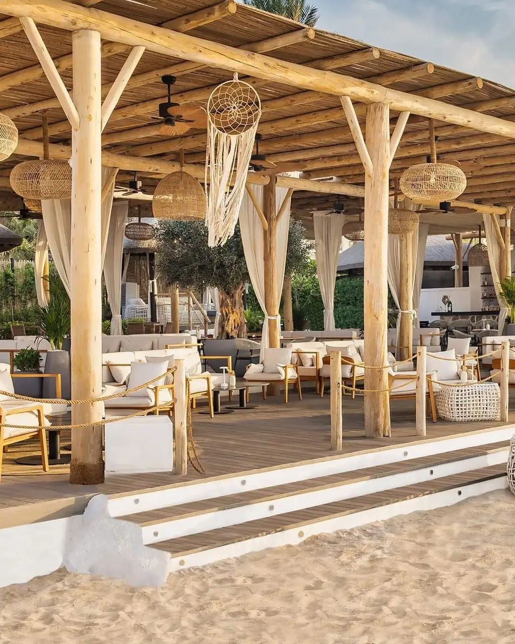 Beach club con estructura y techo de postes y varas de eucalipto al atardecer